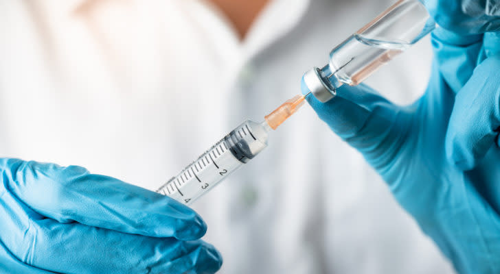 Hands of medical professional holding a syringe, symbolizing PFE, MRNA stock.