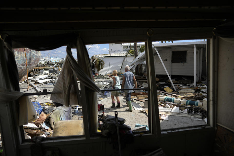 FILE - Snowbirds Bruce and Kathy Hickey, both 70, are seen through the windows of a trailer that had been waterfront, as they look at the wreckage of the trailer park where they had a winter home, originally purchased by Kathy's mother in 1979, on San Carlos Island, Fort Myers Beach, Fla., Wednesday, Oct. 5, 2022, one week after the passage of Hurricane Ian. Hurricane Ian confounded one key computer forecast model, creating challenges for forecasters and Florida residents. (AP Photo/Rebecca Blackwell, File)