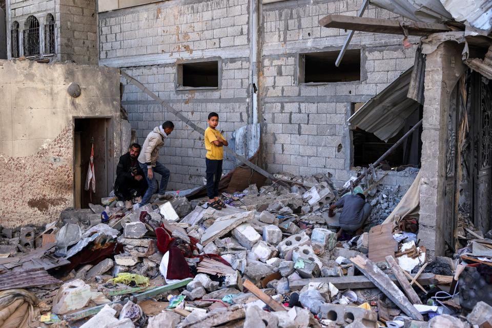 Men and a boy inspect the site of a building that was hit by Israeli bombardment in Rafah in the southern Gaza Strip on 8 May 2024 amid the ongoing conflict in the Palestinian territory between Israel and the militant group Hamas (AFP via Getty Images)