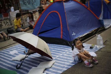 A girl sits next to an umbrella at an area blocked by pro-democracy protesters in Causeway Bay, Hong Kong, October 11, 2014. REUTERS/Carlos Barria