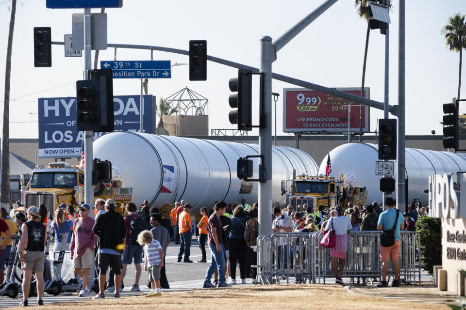 Spectators watch as two rocket motors are slowly moved down Figueroa Street in Los Angeles on Wednesday Oct. 11, 2023. The giant rocket motors, required to display the retired NASA space shuttle Endeavour as if it’s about to blast off, were trucked over two days from Mojave Air and Space Port to LA’s Exposition Park. (AP Photo/Richard Vogel)