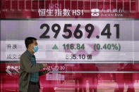 A man walks past a bank's electronic board showing the Hong Kong share index at Hong Kong Stock Exchange in Hong Kong Tuesday, March 2, 2021. Asian stock markets were mixed Tuesday after Wall Street rose as investor concern about possible higher interest rates receded. (AP Photo/Vincent Yu)