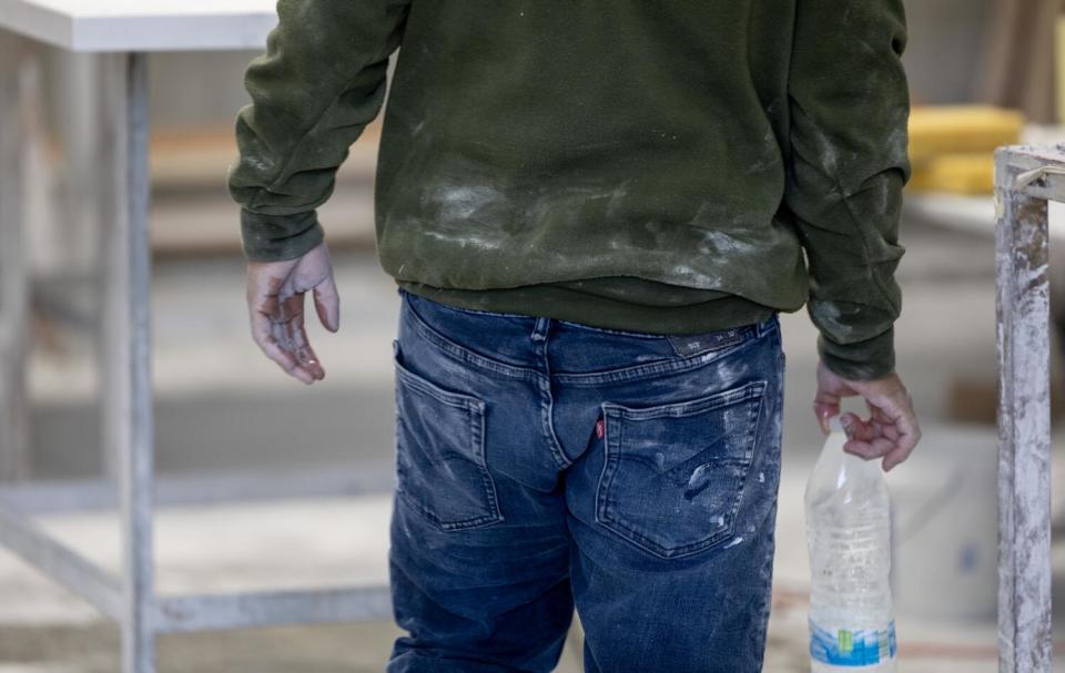 A stone countertop fabricator's clothes are covered in dust.