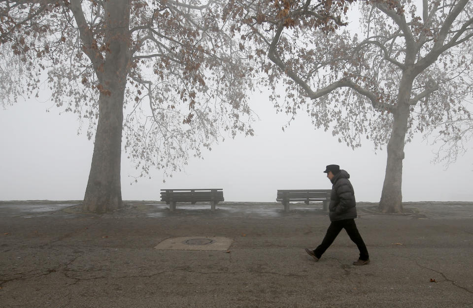 A man walks on the banks of Danube river in Belgrade, Serbia, Wednesday, Jan. 15, 2020. Serbia's government on Wednesday called an emergency meeting, as many cities throughout the Balkans have been hit by dangerous levels of air pollution in recent days, prompting residents' anger and government warnings to stay indoors and avoid physical activity.(AP Photo/Darko Vojinovic)