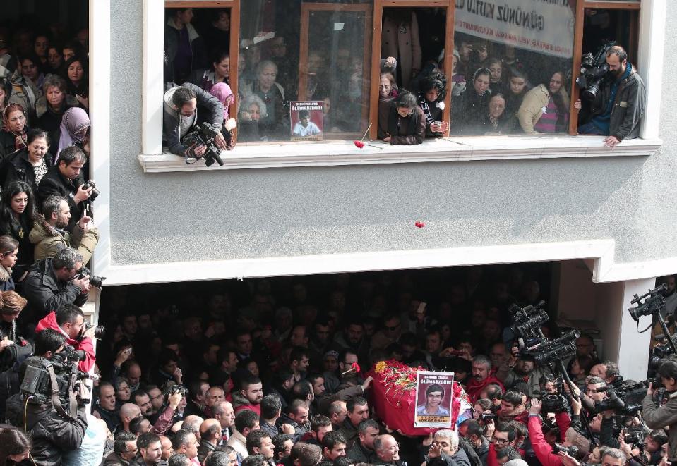 Family member watch from windows as people carry the coffin of Berkin Elvan, a Turkish teenager who was in a coma since being hit on the head by a tear gas canister fired by police during anti-government protests in the summer of 2013, during his funeral in Istanbul, Turkey, Wednesday, March 12, 2014. On Wednesday, thousands converged in front of a house of worship calling for Prime Minister Recep Tayyip Erdogan to resign.(AP Photo/Emrah Gurel)