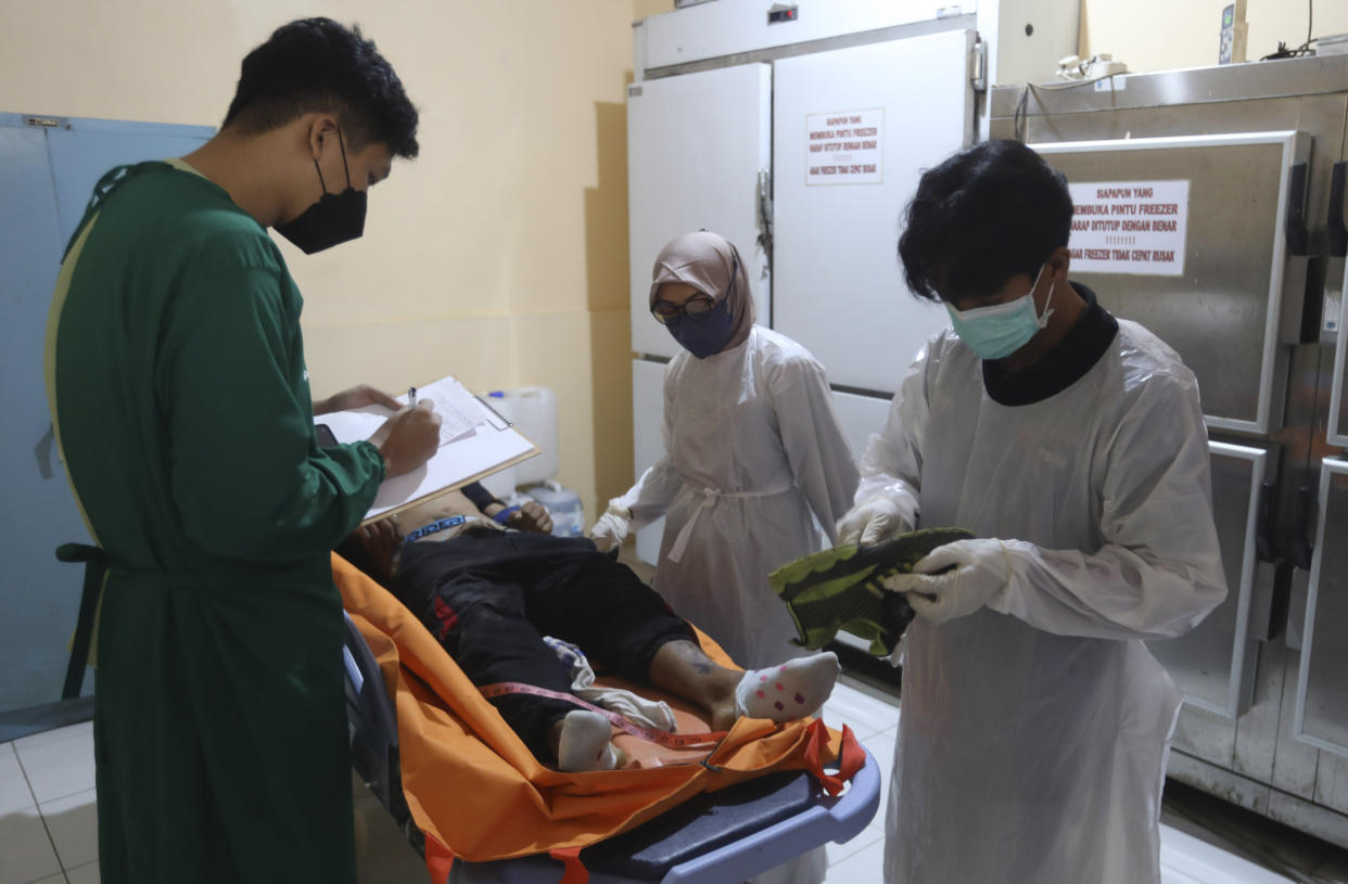 Medical workers identify one of the victims of a soccer match stampede at the Saiful Anwar Hospital in Malang, East Java, Indonesia, Sunday, Oct. 2, 2022. Panic at an Indonesian soccer match after police fired tear gas to to disperse supporters invading the pitch left over 100 people dead, mostly trampled to death, police said Sunday. (AP Photo/Trisnadi)