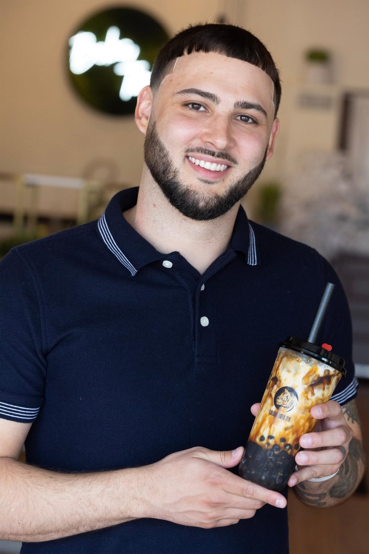 Maverick Sales holds a cup of his signature Golden Tiger Milk Tea, which is a milk tea made with tapioca boba pearls.