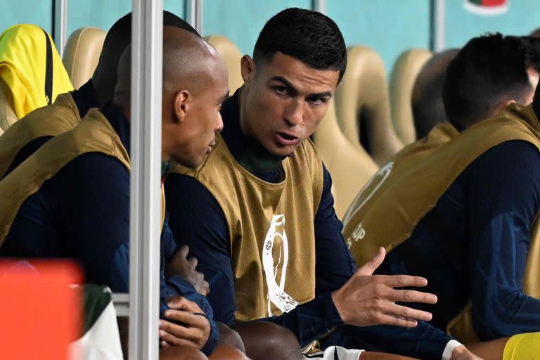 Portugal's forward #07 Cristiano Ronaldo (R) speaks with Portugal's midfielder #17 Joao Mario on the bench during the Qatar 2022 World Cup quarter-final football match between Morocco and Portugal at the Al-Thumama Stadium in Doha on December 10, 2022. (Photo by PATRICIA DE MELO MOREIRA / AFP)