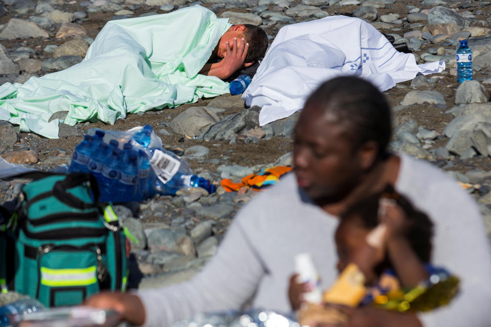 Migrants rest after landing in a dinghy on Aguila beach.