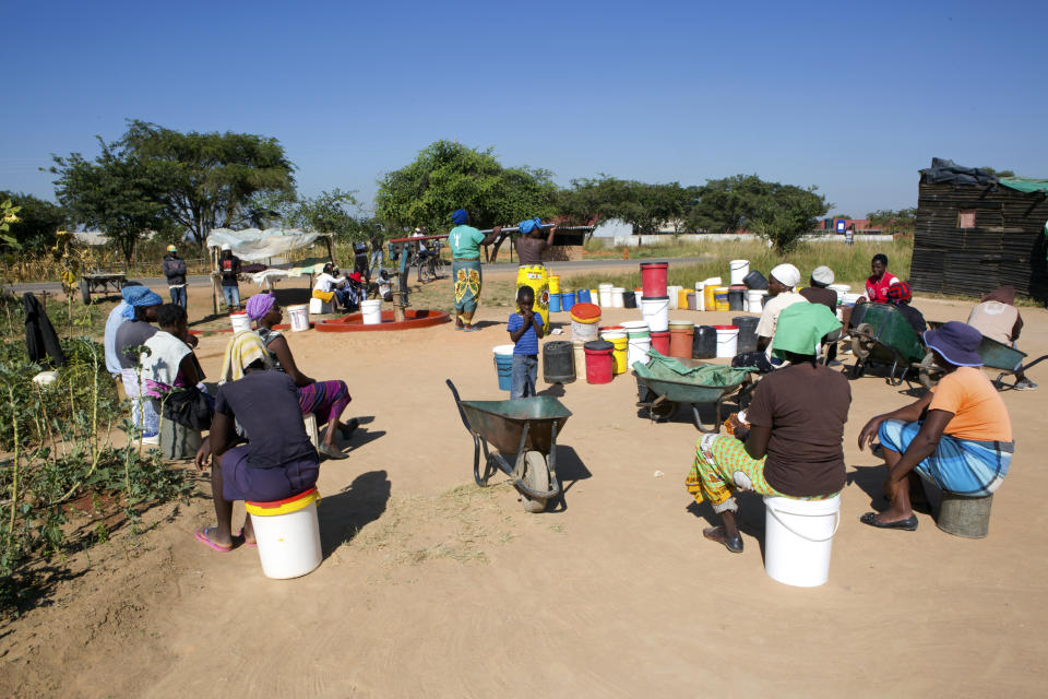 In this March, 31, 2020, photo, women and children wait for their turn to fetch water in a poor suburb of Harare, Zimbabwe. For people around the world who are affected by war and poverty, the simple act of washing hands is a luxury, even during the coronavirus pandemic. In Zimbabwe, clean water is often saved for daily tasks like doing dishes and flushing toilets. (AP Photo/Tsvangirayi Mukwazhi)