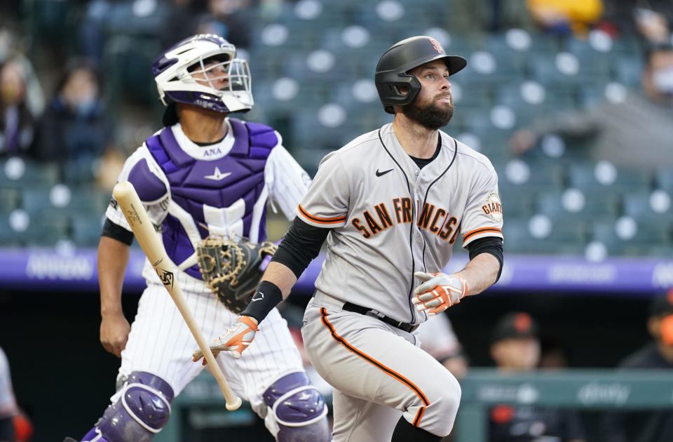 San Francisco Giants' Brandon Belt, front, follows the flight of his two-run home run with Colorado Rockies catcher Elias Diaz in the first inning of game two of a baseball doubleheader Tuesday, May 4, 2021, in Denver. (AP Photo/David Zalubowski)