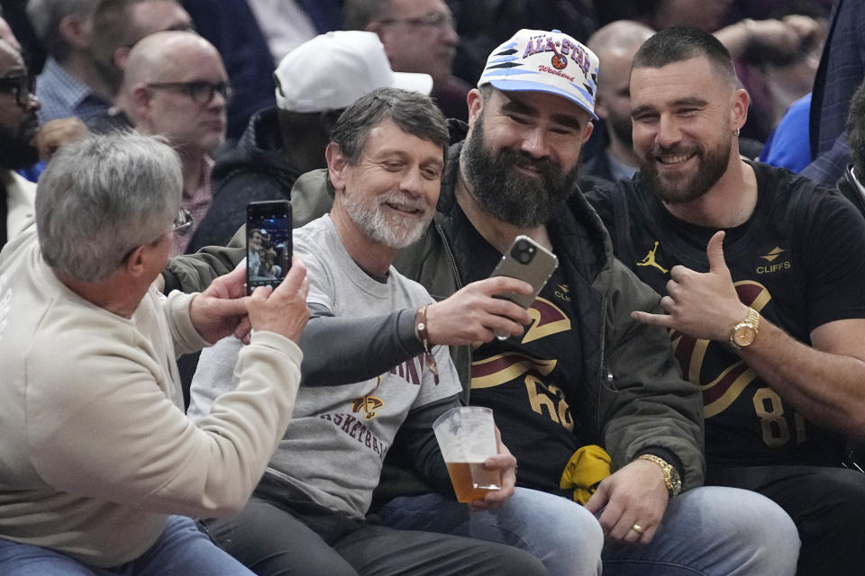 Jason Kelce, second from right, and Travis Kelce, right, pose for a photo with fans courtside at the Celtics-Cavaliers NBA basketball game, Tuesday, March 5, 2024, in Cleveland. (AP Photo/Sue Ogrocki)