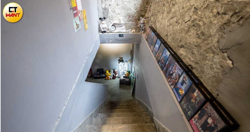 從一樓通往地下室的樓梯旁，陳列了不少老闆用生活照做成電影海報的錄影帶盒。（圖／焦正德攝）