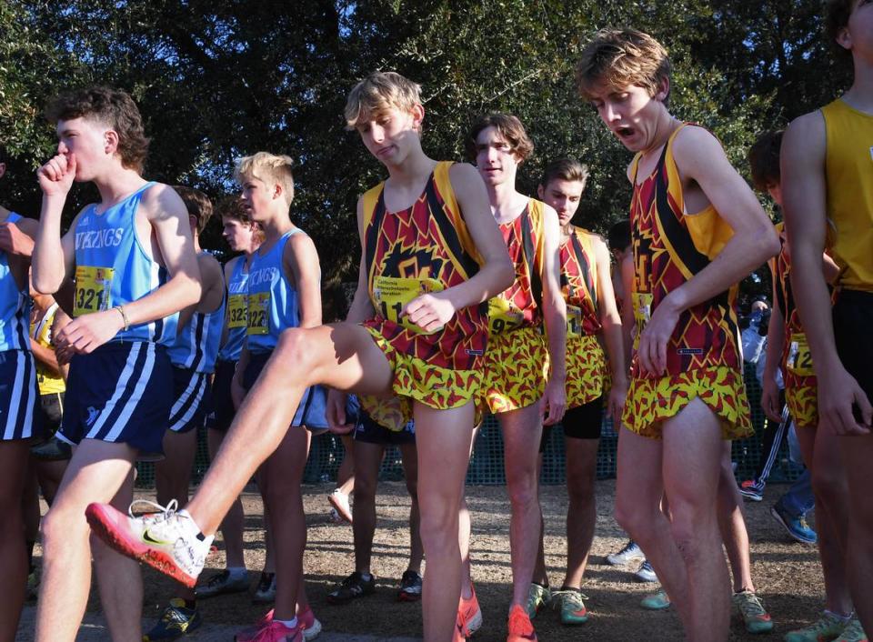 Oakdale’s Caleb Cavanaugh, left, kicks his leg with Dax Daley to the right at the start of the Boys Division III race at the CIF state cross country championships held at Woodward Park Saturday, Nov. 27, 2021 in Fresno.
