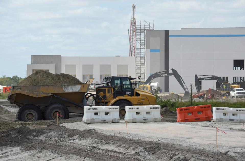 Construction crew members continue their work on the new Amazon warehouse at the Midway Business Park on Tuesday, April 12, 2022, in Port St. Lucie.