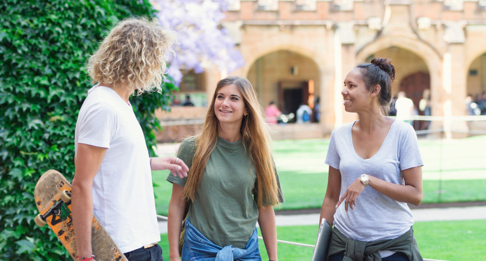 University students smile and talk on a campus.