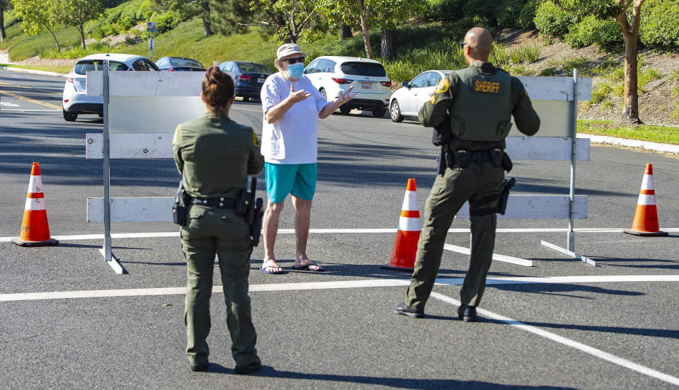 After being evacuated due to the Silverado Fire, a man pleads with an Orange County Sheriff's deputy at the intersection of Lake Forest and Rue de Valore to let him return to his home in Foothill Ranch, Wednesday, Oct. 28, 2020. (Mark Rightmire/The Orange County Register via AP)