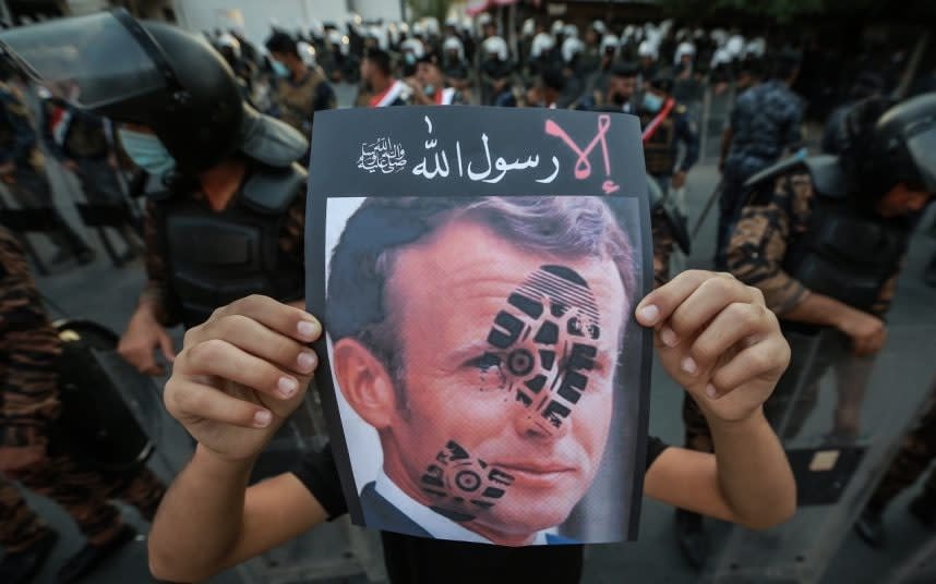 A demonstrator holds a picture of Emmanuel Macron outside the French embassy in Baghdad