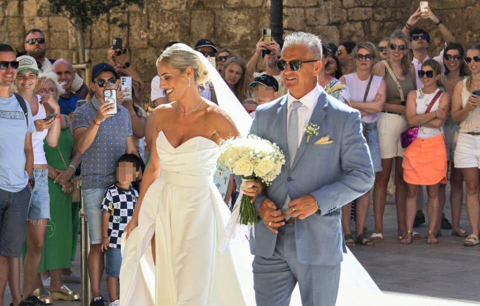 Cristina, del brazo de su padre y padrino de la boda, rumbo al altar a las puertas de la iglesia donde se encontraban algunos curiosos