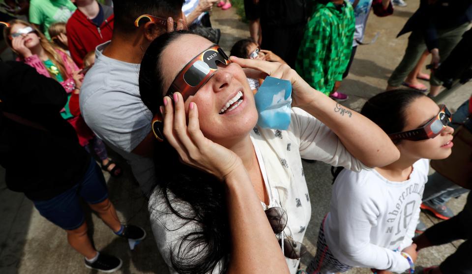 Heather Sandoval, of Des Moines, Iowa, holds her glasses on during an eclipse watch party, Monday, Aug. 21, 2017, in Des Moines, Iowa. (AP Photo/Charlie Neibergall)