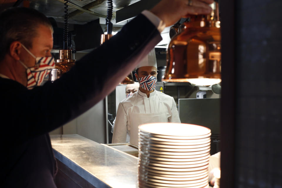 A waiter and a kitchen assistant wait for customers in the Alain Ducasse's restaurant « Allard », in Paris, Thursday, June 11, 2020. French Michelin-starred chef Alain Ducasse unveils virus-protection measures as he prepares to reopen his restaurants, including a new filtration system that works to stop virus particles from the air traveling to neighboring tables. (AP Photo/Thibault Camus)