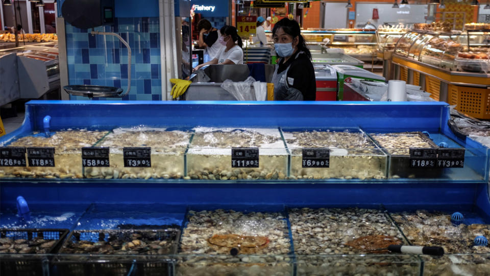 A salesperson wearing a face mask stands at a seafood stall in a supermarket following the confirmation of new SARS-CoV-2 cases in Beijing. Source: AAP