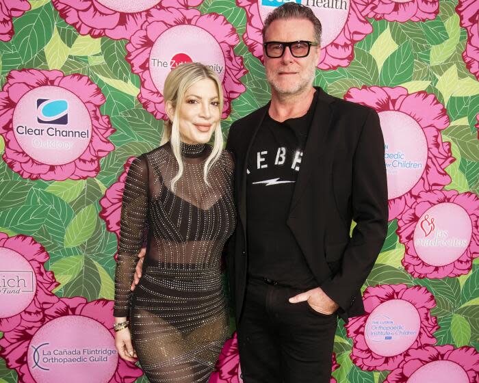 Tori Spelling, left, and Dean McDermott pose together against a floral background