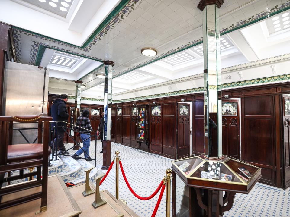 People enter the public toilets of the Lavatory de La Madeleine, which features historical artefacts in a display case