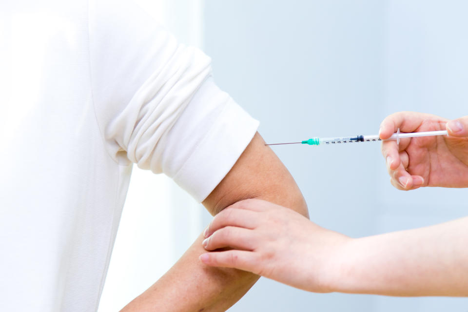 Nurse holding syringe making vaccination injection in shoulder of female patient. Flu influenza vaccine clinical trials concept, corona virus treatment side effect, inoculation.