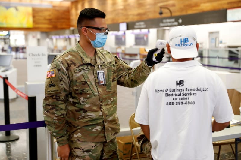 FILE PHOTO: A Hawaii National Guardsman checks the temperature of a traveler at the Daniel K. Inouye International Airport during the spread of the coronavirus disease (COVID-19) in Honolulu