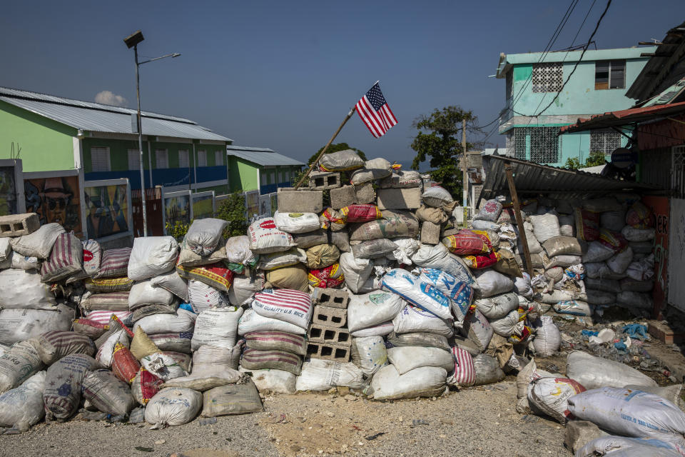 A U.S. national flag tops a barricade delimiting territorial gang control in the Bel Air neighborhood of Port-au-Prince, Haiti, Saturday, Sept. 25, 2021. More than a city, Port-au-Prince is an archipelago of gang-controlled islands. Some neighborhoods are abandoned. Others are barricaded behind fires, destroyed cars and piles of garbage, occupied by heavily armed men. (AP Photo/Rodrigo Abd)