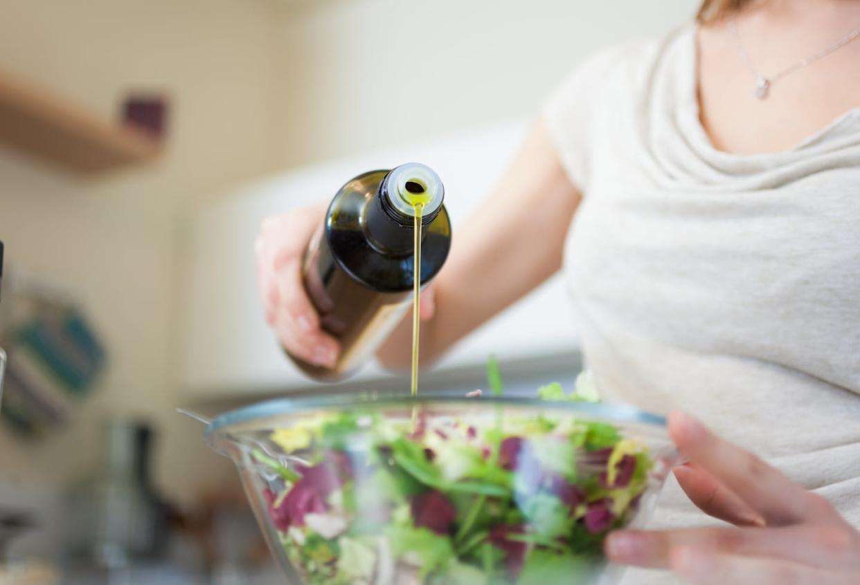 Mujer aliñando una ensalada con aceite de oliva. <a href="https://www.shutterstock.com/es/image-photo/woman-preparing-salad-135035993" rel="nofollow noopener" target="_blank" data-ylk="slk:Minerva Studio/Shutterstock;elm:context_link;itc:0;sec:content-canvas" class="link ">Minerva Studio/Shutterstock</a>