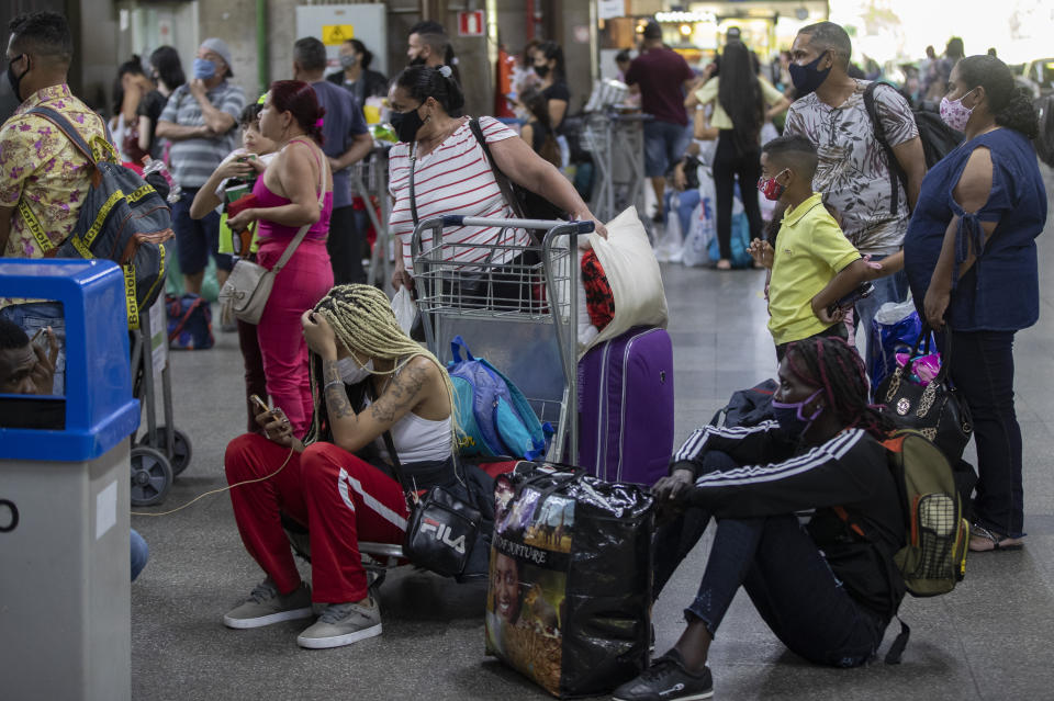 Travelers wait to board an inter-state bus, amid the COVID-19 pandemic in Sao Paulo, Brazil, Wednesday, Dec. 30, 2020. Despite rising infection numbers in the country, Brazilians are flocking to airports and taking to the highways to visit friends and loved ones to usher in the new year and take advantage of a long weekend. (AP Photo/Andre Penner)