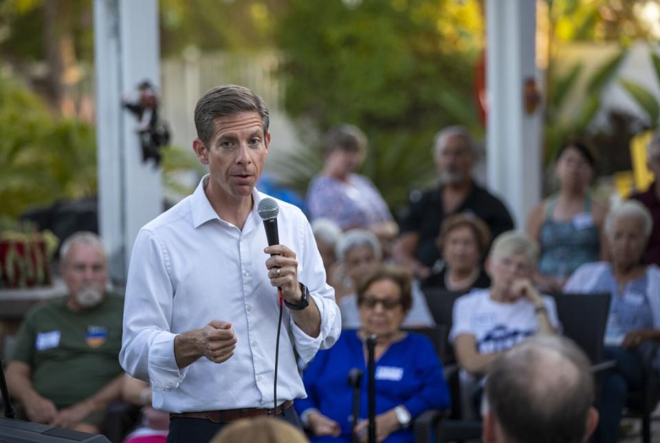 A man holds a microphone and talks to people.