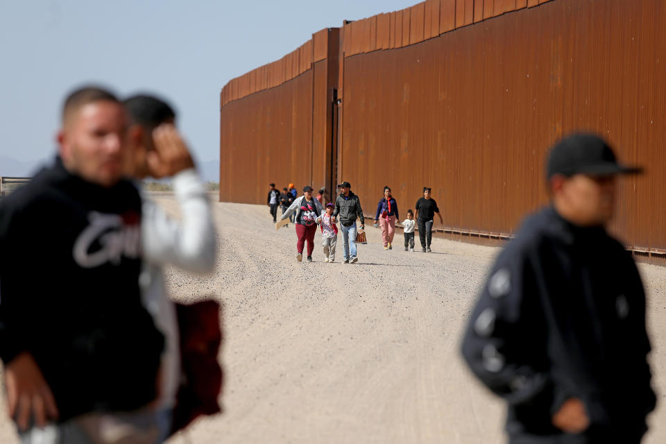 Immigrants walk along the border wall to turn themselves over to Border Patrol agents along the U.S.-Mexico border on Thursday, May 11, 2023 in San Luis Rí­o Colorado in Mexico. / Credit: Gary Coronado / Los Angeles Times via Getty Images