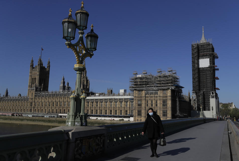 A woman walks near Britain's Houses of Parliament as the country is in lockdown to help curb the spread of coronavirus, in London, Tuesday, April 21, 2020. Britain's Parliament is going back to work, and the political authorities have a message for lawmakers: Stay away. U.K. legislators and most parliamentary staff were sent home in late March as part of a nationwide lockdown to slow the spread of the new coronavirus. With more than 16,500 people dead and criticism growing of the government’s response to the pandemic, legislators are returning Tuesday — at least virtually — to grapple with the crisis. (AP Photo/Kirsty Wigglesworth)