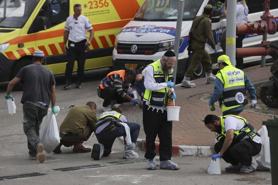 Members of Israeli Zaka Rescue and Recovery team and Israeli soldiers clean blood from the site of an attack, at the Ariel Industrial Zone, near the West Bank Jewish settlement of Ariel, Tuesday, Nov. 15, 2022. A Palestinian killed two Israelis and wounded four others in an attack in a settlement in the occupied West Bank on Tuesday before he was shot and killed by Israeli security personnel, Israeli paramedics and Palestinian officials said. (AP Photo/Oren Ziv)