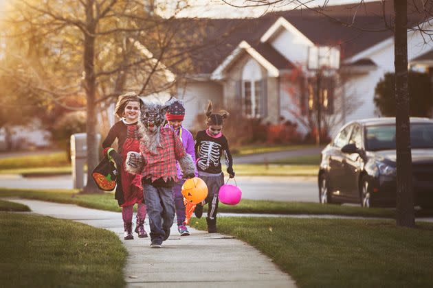 Children trick or treat on Halloween in a stock image.