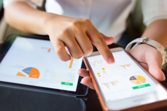 Woman pointing at charts on a smartphone and tablet.