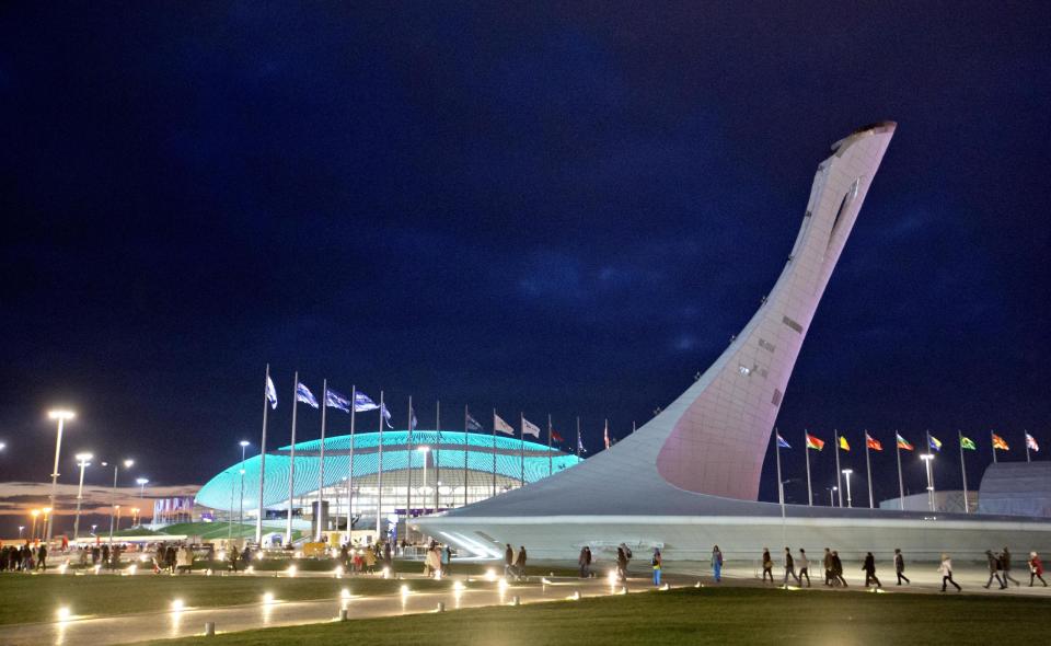 Spectators walk by the Bolshoy Ice Dome at left and the Olympic cauldron on their way to the rehearsal of the opening ceremony at the 2014 Winter Olympics, Saturday, Feb. 1, 2014, in Sochi, Russia. (AP Photo/David Goldman)