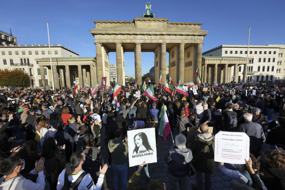 FILE - People gather in front of the Brandenburg Gate to protest against the government in Iran in memory of Mahsa Amini, a young Iranian woman who died after being arrested in Tehran by Iran's 'morality police', in Berlin, Germany, Friday, Oct. 7, 2022. As anti-government protests roil cities and towns in Iran for a fourth week, sparked by the death of Amini, tens of thousands of Iranians living abroad have marched on the streets of Europe, North America and beyond in support of what many believe to be a watershed moment for their home country. (AP Photo/Michael Sohn, File)