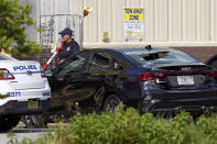 A law enforcement officer walks by a car with bullet holes in the windshield in front of a Dollar General store, Sunday, Aug. 27, 2023, in Jacksonville, Fla., at the scene of a mass shooting a day earlier. (AP Photo/John Raoux)