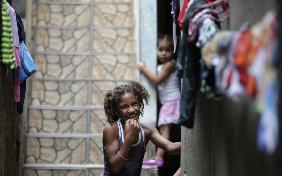 A girl smiles outside her home at the Mare slums complex in Rio de Janeiro