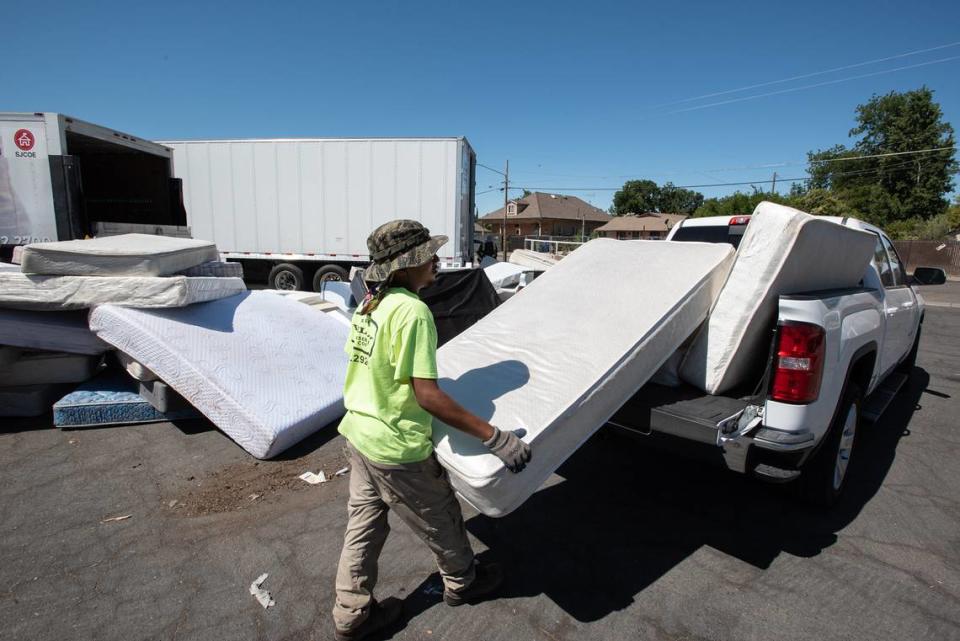 California Conservation Corp member Anthony Williams unloads mattresses during a Modesto city sponsored trash day at John Thurman Field in Modesto, Calif., on Saturday, June, 25, 2022. The mattresses and box springs are recycled by Bye Bye Mattress.