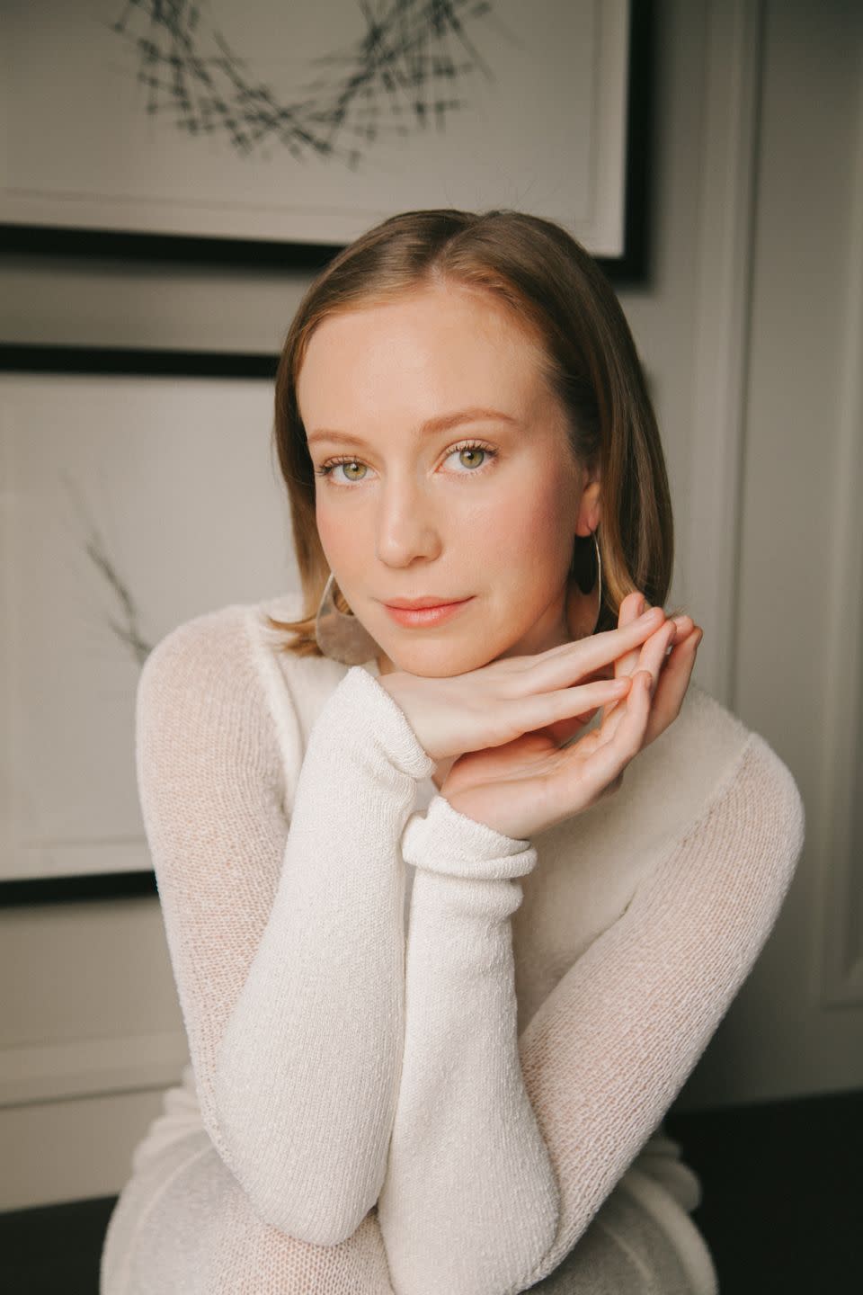 hannah einbinder posing in a white dress with her hands folded beneath her chin