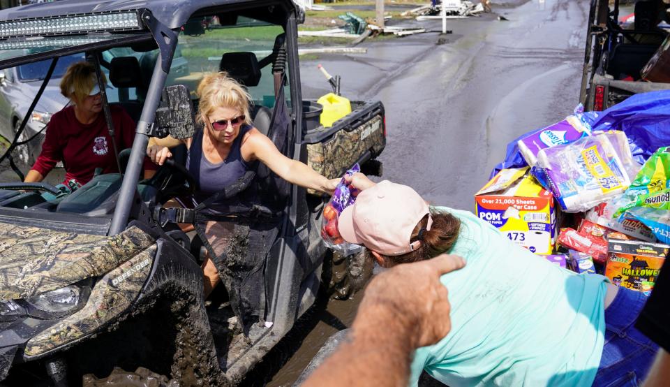 Tess Coulon hands supplies to a resident of the island of Barataria, La.