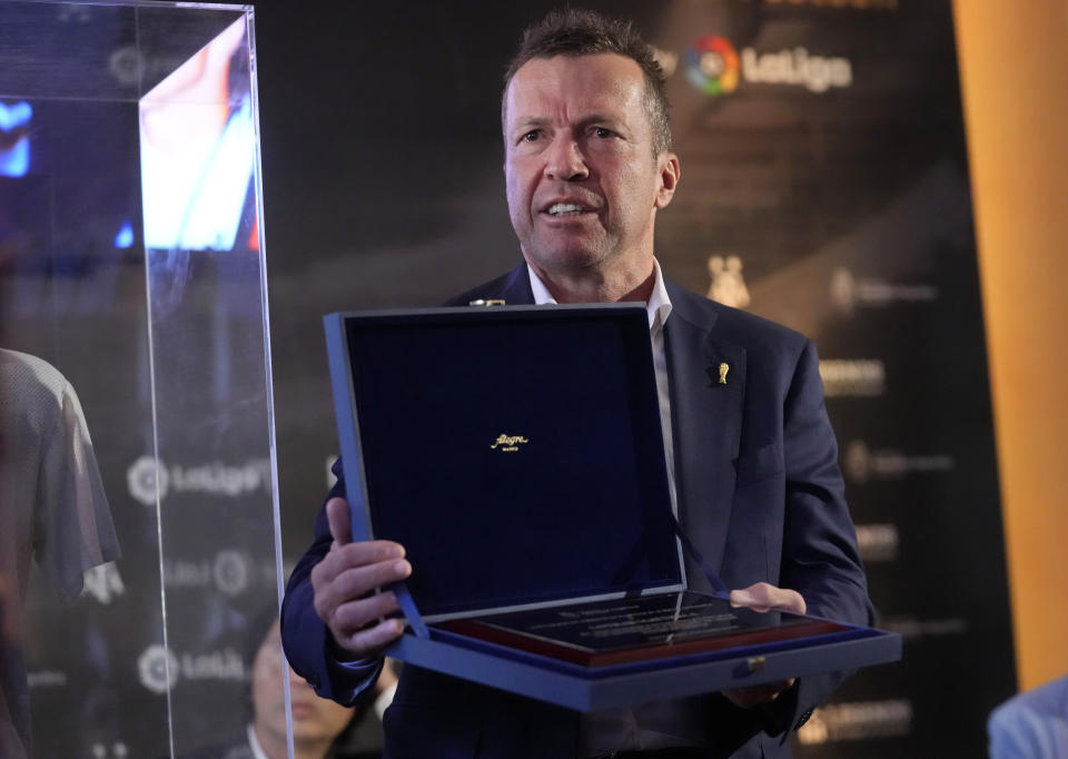 El retirado futbolista alemán Lothar Matthaus muestra un obsequio entregado por la embajada de Argentina en España tras donar la camiseta que Diego Maradona lució en la final del Mundial de 1986 en México, el jueves 25 de agosto de 2022. (AP Foto/Paul White)