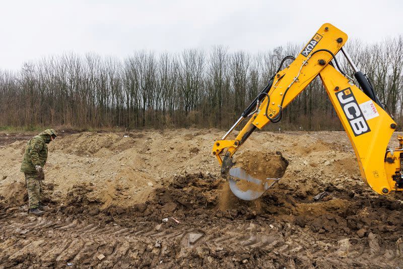 Croatian soldier is seen next to excavators during digging on newly discovered mass grave with 11 bodies near Vukovar