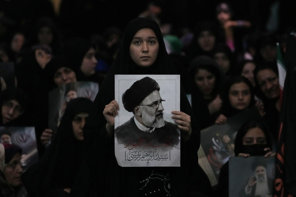 A woman holds a poster of the late Iranian President Ebrahim Raisi at mam Khomeini Grand Mosque in Tehran, Iran, Tuesday, May 21, 2024, during a funeral ceremony for him and his companions who were killed in a helicopter crash on Sunday in a mountainous region of the country's northwest. Mourners in black began gathering Tuesday for days of funerals and processions for Iran's late president, foreign minister and others killed in a helicopter crash, a government-led series of ceremonies aimed at both honoring the dead and projecting strength in an unsettled Middle East. (AP Photo/Vahid Salemi)