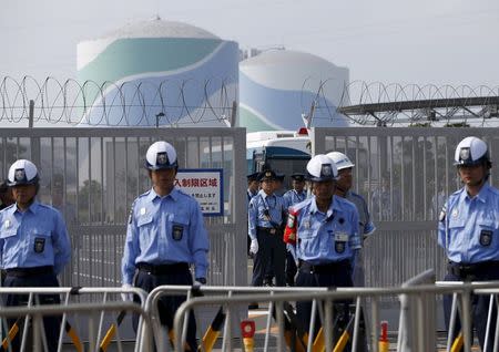 Police officers and security personnel stand guard at an entrance of Kyushu Electric Power's Sendai nuclear power station, during a protest demanding for the stop of the plant's restart, in Satsumasendai, Kagoshima prefecture, Japan August 9, 2015. REUTERS/Issei Kato/Files